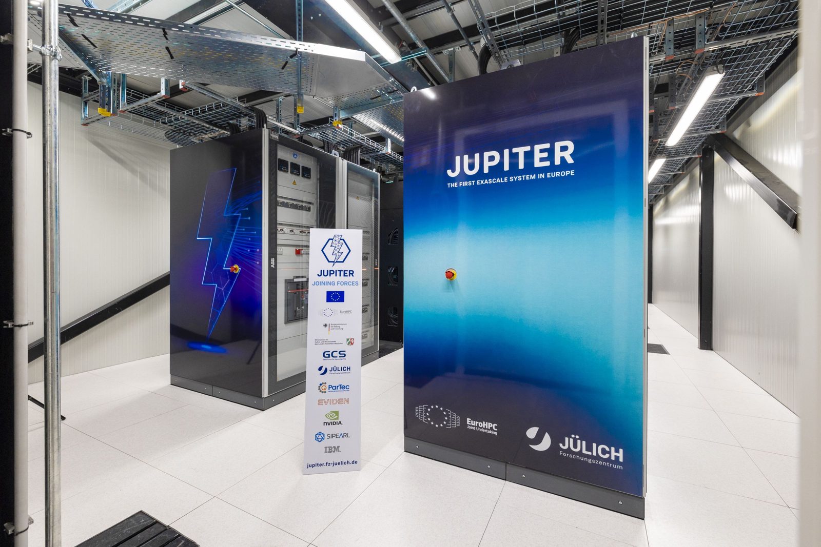 JUPITER supercomputer racks at Forschungszentrum Jülich with a blue JUPITER banner and partner logos